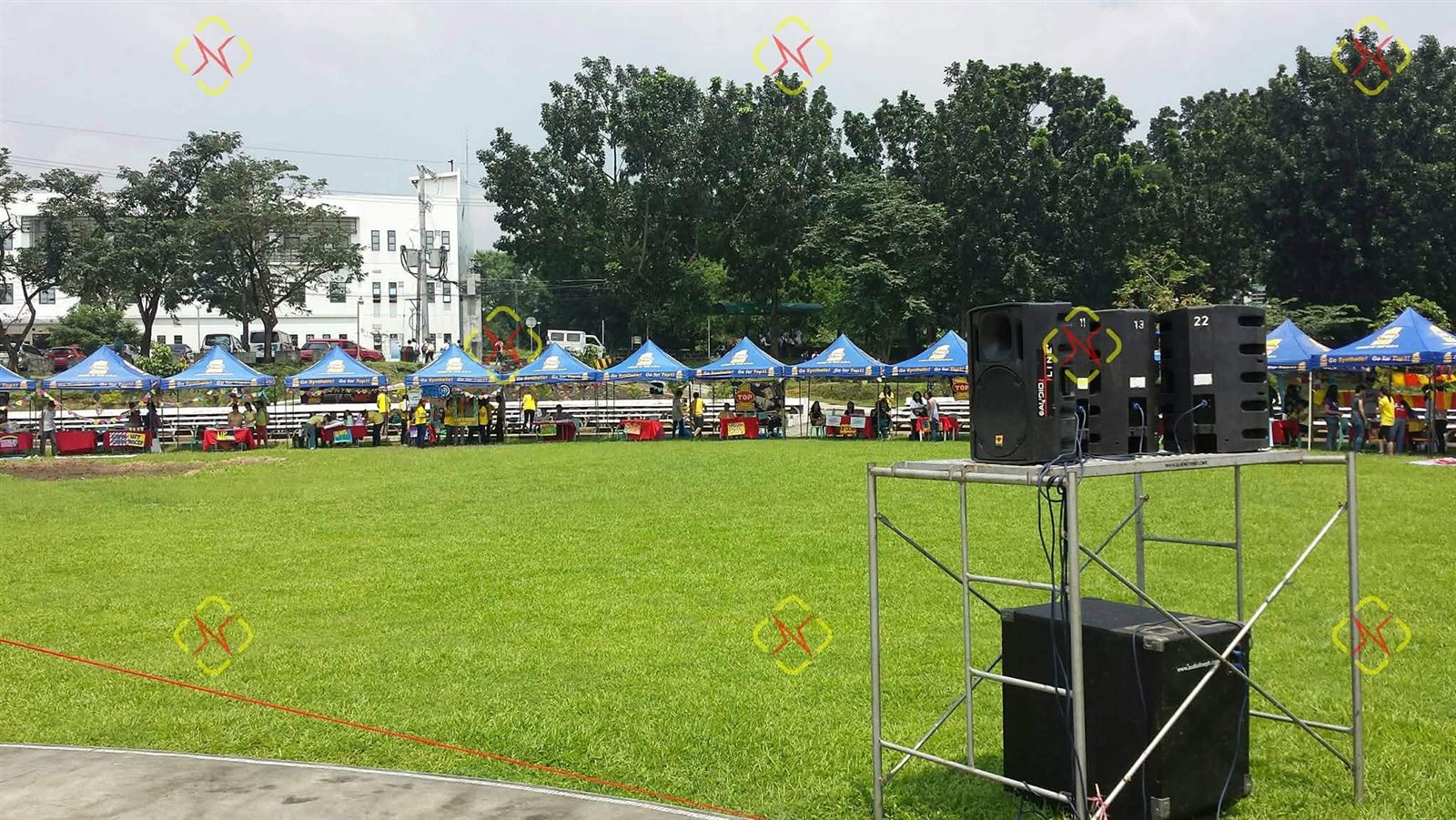 Outdoor sound system towers positioned across a large event lawn